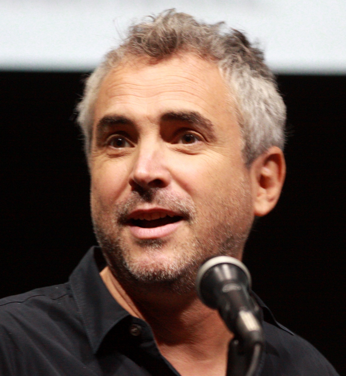 Alfonso Cuarón speaking into a microphone at San Diego Comic-Con in 2013