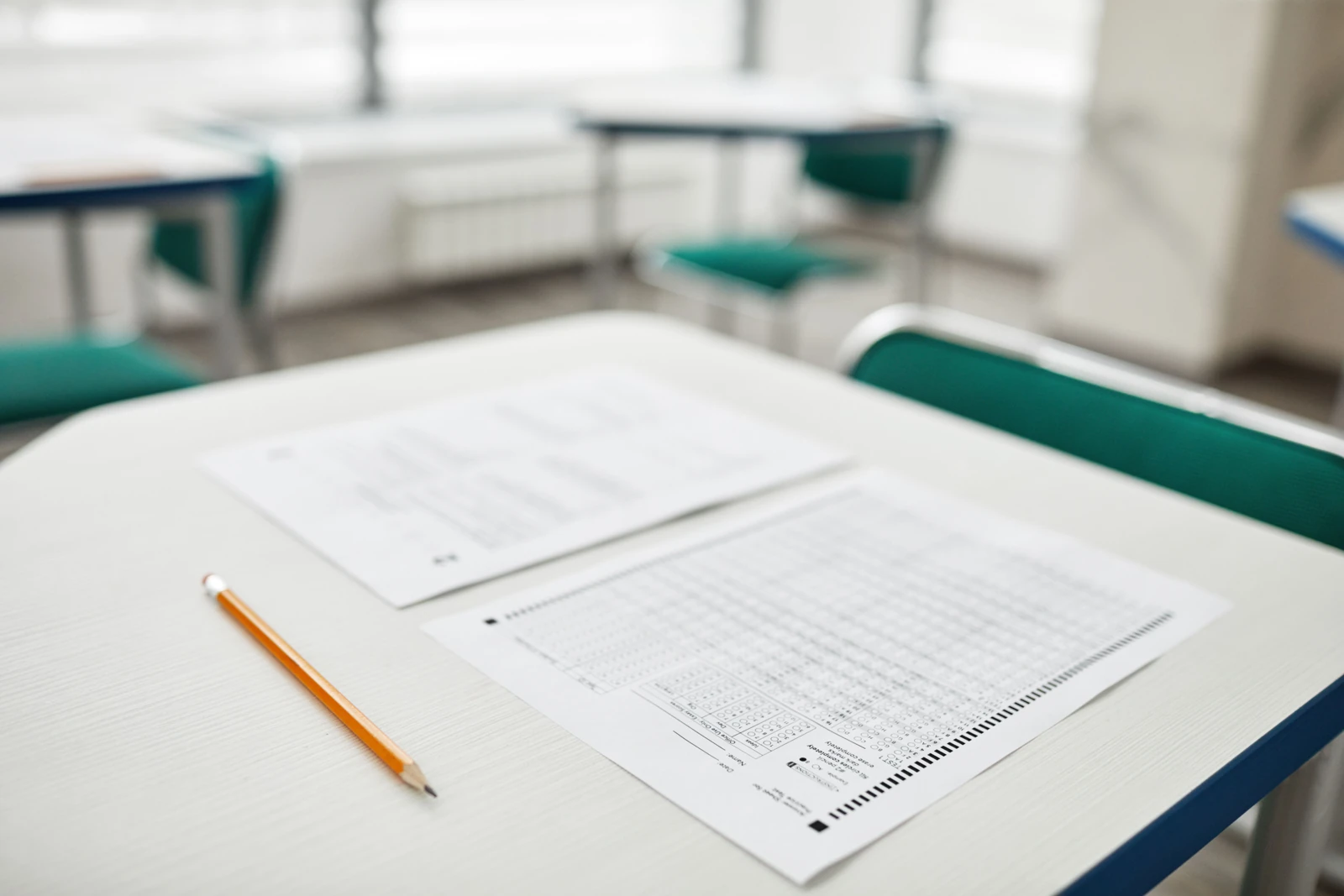 A pencil and printed assessment sheets lie on a classroom desk.