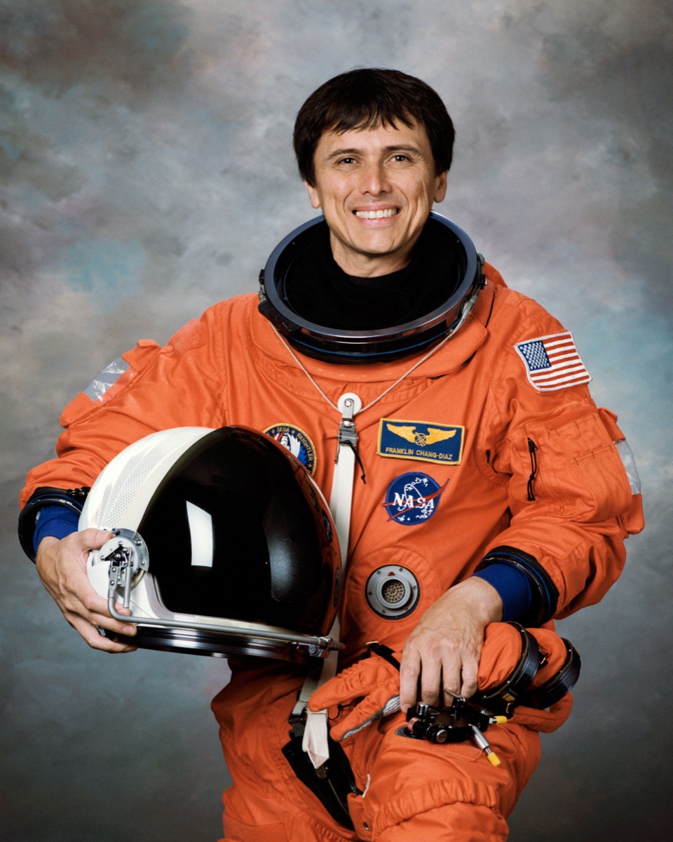 Franklin Chang-Díaz in an orange NASA astronaut suit holding his helmet