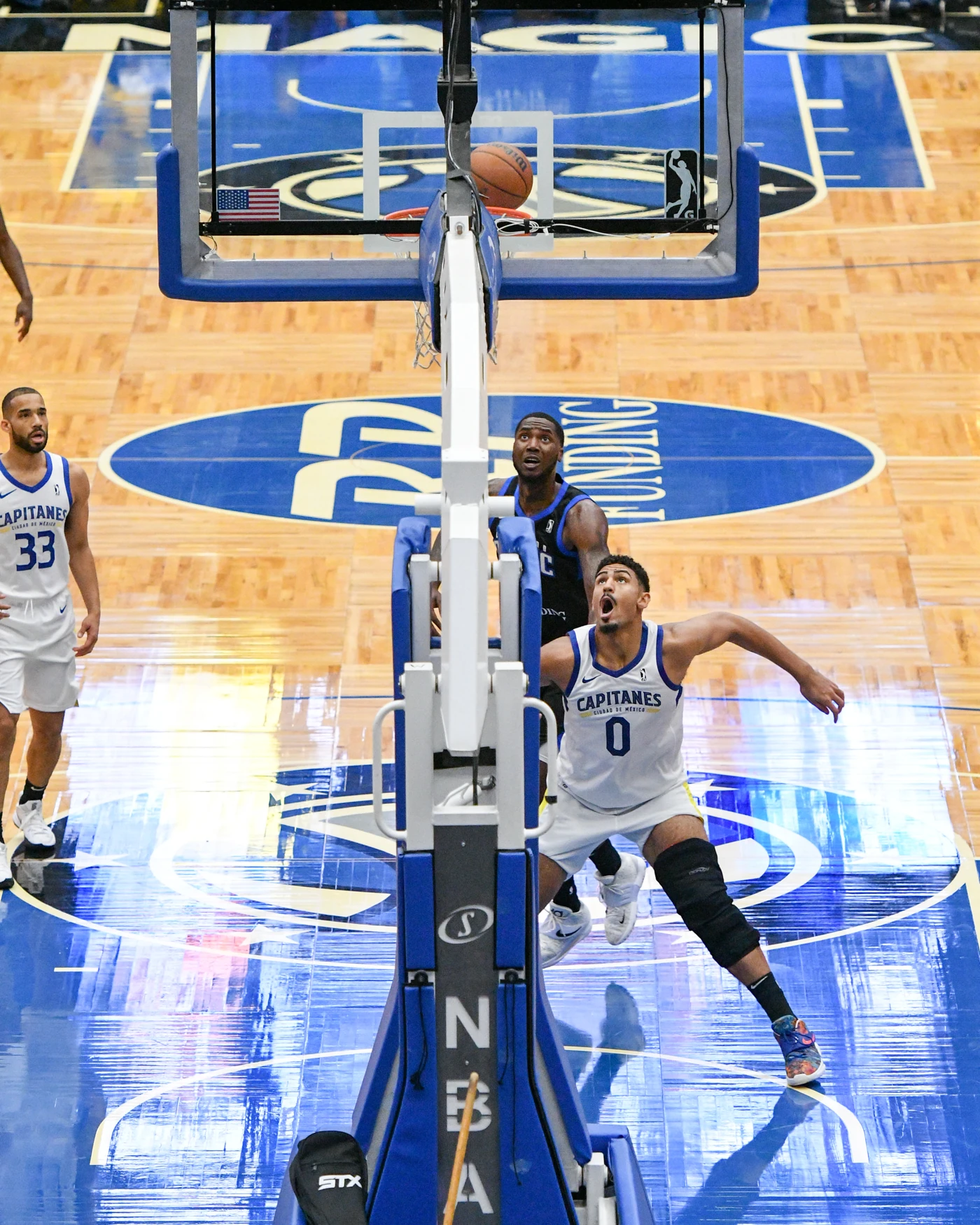 Capitanes players in white watch the ball at the basket during a 2021 game against the Lakeland Magic.
